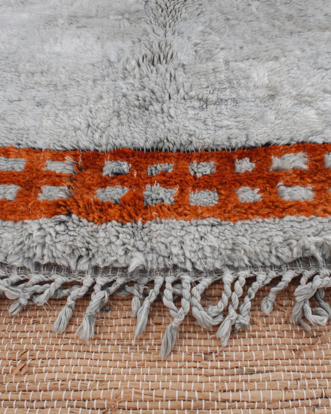 Cream Ivory Moroccan Berber Wool Rug with Sunset Orange Border, handmade in Bhadohi India – close-up of a shaggy light gray rug with a horizontal orange band featuring