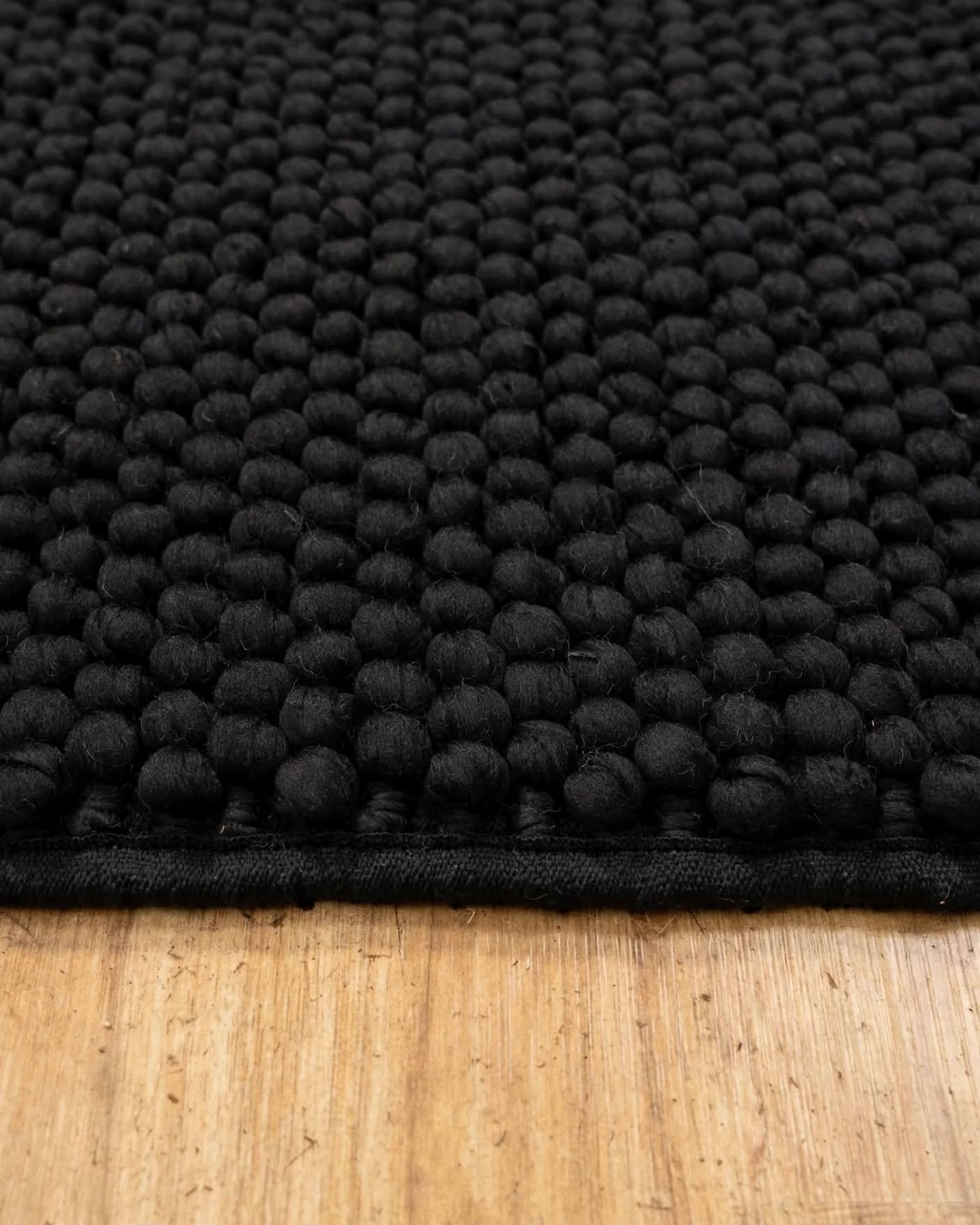 Charcoal Black Chunky Wool Area Rug, handmade in Bhadohi India – close-up of a black textured area rug with a raised tufted pattern, shown