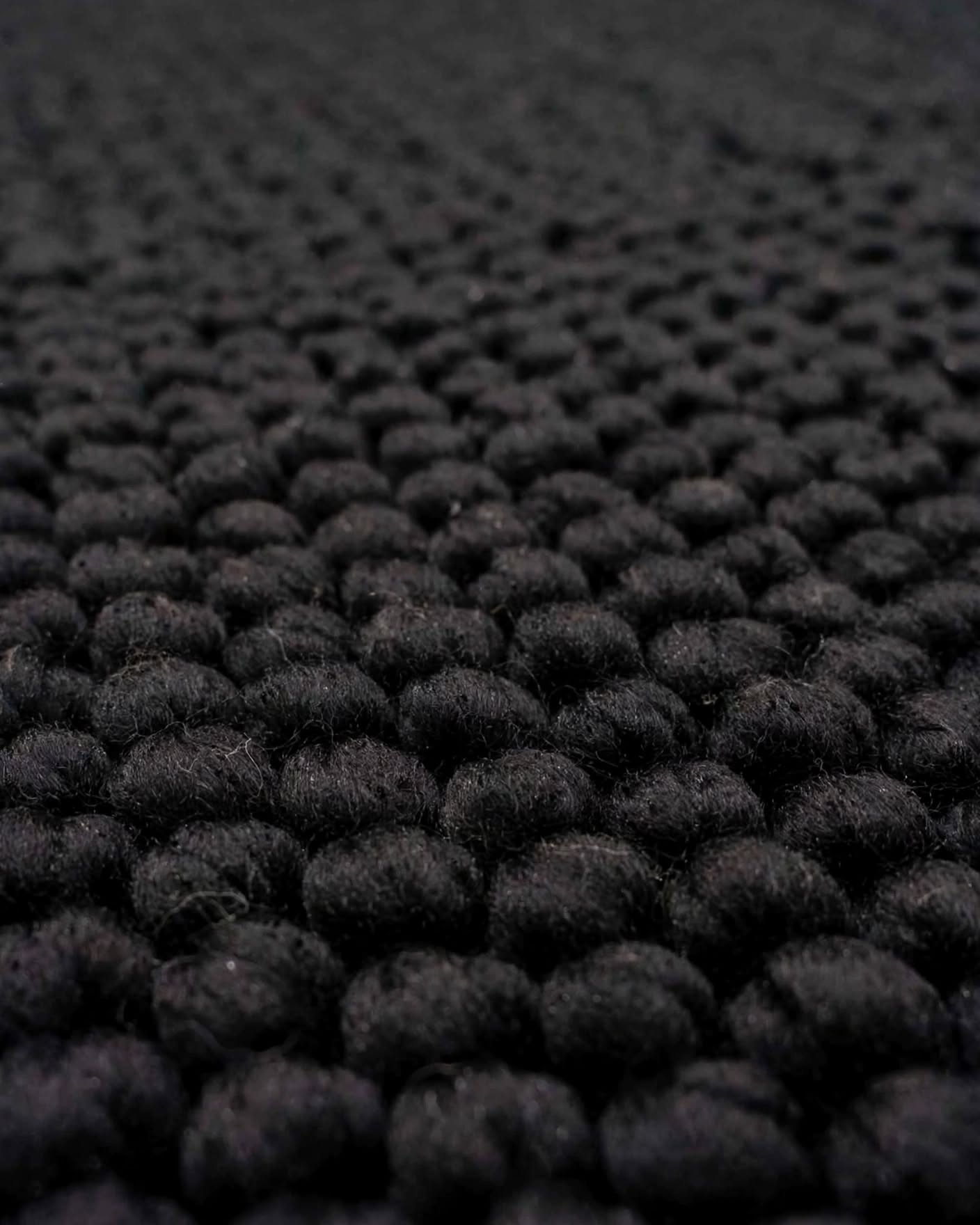 Charcoal Black Chunky Wool Area Rug, handmade in Bhadohi India – close-up of a black textured rug with a dense, looped tufted pattern