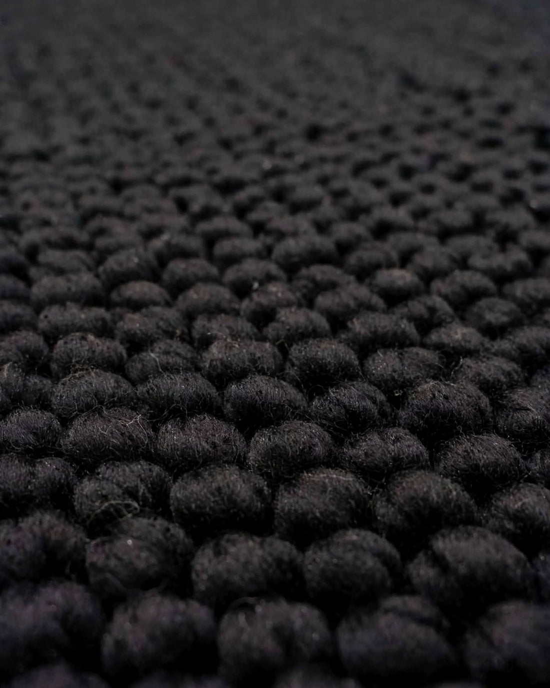 Charcoal Black Chunky Wool Area Rug, handmade in Bhadohi India – close-up of a black textured rug with a dense, looped tufted pattern