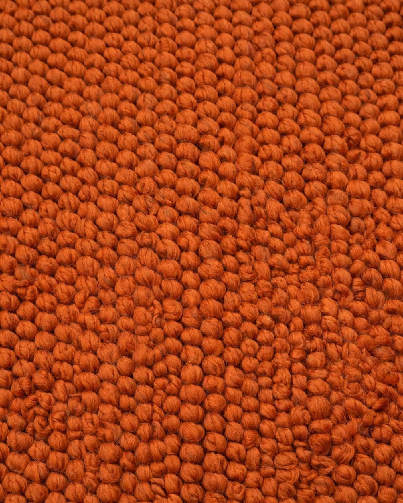 Terracotta Rust Chunky Wool Area Rug, handmade in Bhadohi India – a close-up of a textured orange loop-pile carpet or rug, showing the dense,