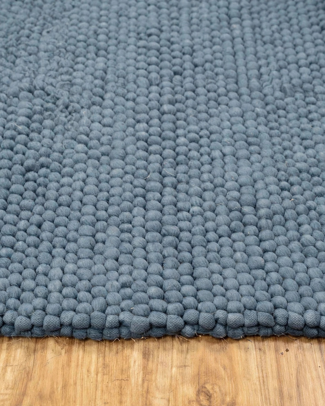 Denim Blue Chunky Wool Area Rug, handmade in Bhadohi India – a close-up of a textured blue-gray wool loop rug with a chunky, bumpy surface,
